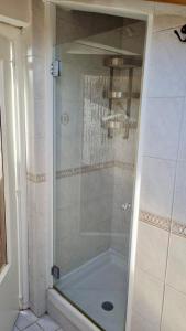 La salle de bains est pourvue d'une douche avec une porte en verre. dans l'établissement the Wooden Roof, à Baronissi