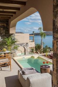 eine Außenterrasse mit einem Pool, einem Tisch und Stühlen in der Unterkunft Elounda Infinity Exclusive Resort & Spa - Adults Only in Elounda