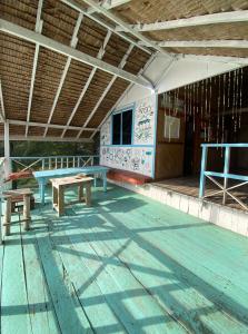 a picnic table and benches on a porch of a building at Ricky's Beach House in Pasarsungai-nyala