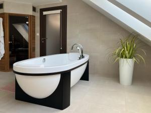 a bathroom with a bath tub and a plant at Lux Apartmán Centrum in Topoľčany