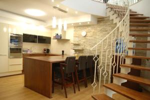 a kitchen with a bar with chairs and a staircase at Lux Apartmán Centrum in Topoľčany +25 photos