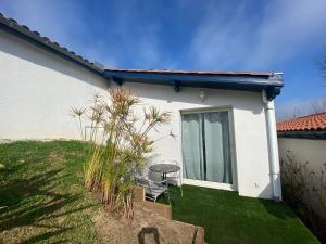 een klein wit huis met een stoel in de tuin bij Ilbarritz, T2 proche plage/parking/terrasse in Bidart