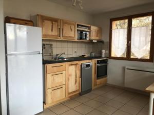 a kitchen with a white refrigerator and wooden cabinets at Le Chamois 2 in Laye