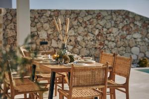 uma mesa de madeira com cadeiras e uma mesa com uma peça central em Thelxi's Suite II - Brand New Seaview Suite! em Volímai