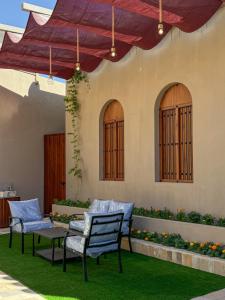 a patio with chairs and a table on grass at بيت أرض الثراء Rich Land House in Nizwa