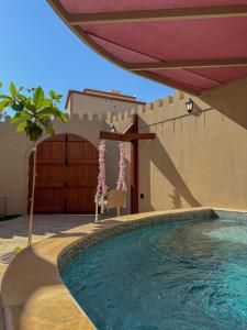 a swimming pool in front of a building with a wall at بيت أرض الثراء Rich Land House in Nizwa
