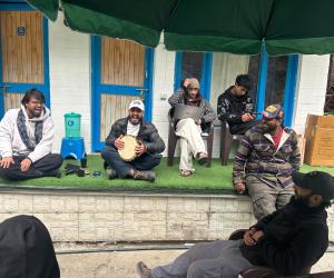 eine Gruppe von Männern, die unter einem Schirm auf dem Boden sitzen in der Unterkunft Tiny Spot Hostel in Manali