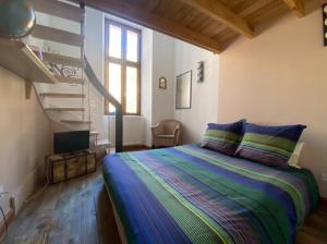 a bedroom with a bed and a spiral staircase at Magnifique appartement 8 couchages dans villa historique in Jausiers