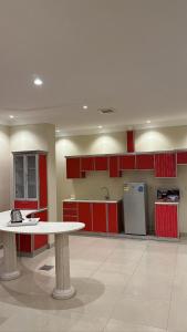 Una cocina grande con gabinetes rojos y una mesa blanca. en فلور الخليجية للشقق المخدومة Flowersuite1, en Dammam 34 fotos más