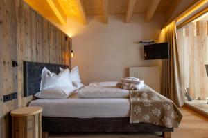 1 dormitorio con 1 cama con sábanas y almohadas blancas en Hotel Rezia en La Villa