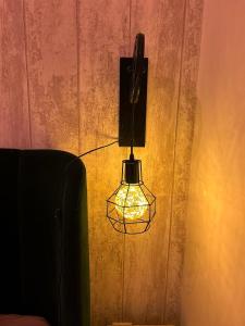 una luz negra colgando de una pared con una lámpara en Mimi's old workshop, en París