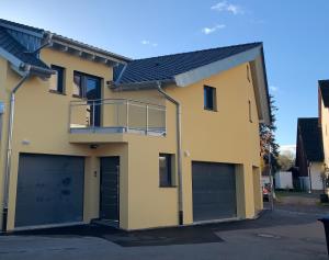 a house with two garage doors and a balcony at 1 Zimmer mit Bad ohne Küche, 1 Person, 15 qm, direkt an der Aach in Singen