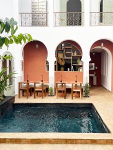 a pool of water in a courtyard with tables and chairs at Riad Al Uzza in Marrakech