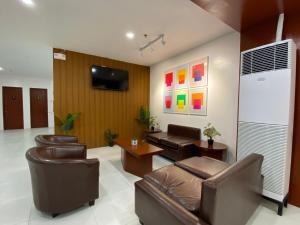 uma sala de estar com cadeiras de couro e uma televisão em Cris Inn Tagum em Tagum
