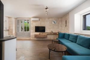 uma sala de estar com um sofá azul e uma televisão em Villa Komelo em Škrip