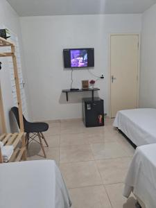 a white room with a tv on a wall at Suítes flor de Mandacaru in Piranhas