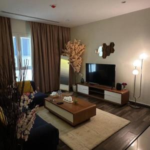 sala de estar con TV de pantalla plana y mesa en شقة انيقة بموقع مميز ودخول ذاتي, en Dhahran
