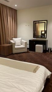 1 dormitorio con cama, silla y espejo en شقة انيقة بموقع مميز ودخول ذاتي, en Dhahran