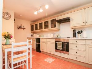 une cuisine avec des armoires blanches et une table et des chaises dans l'établissement Black Sheep Cottage, à Thirsk