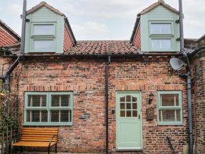 une maison en briques avec un banc devant elle dans l'établissement Black Sheep Cottage, à Thirsk