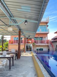 an outdoor patio with tables and a swimming pool at Chai Patchara Resort in Ban Nong Ban Kao