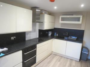 a kitchen with white cabinets and black counter tops at The Heritage Guest House in Montrose