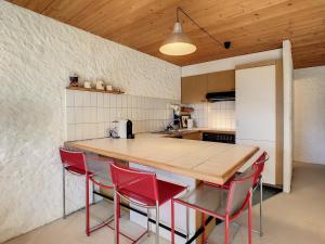 uma cozinha com uma mesa de madeira e cadeiras vermelhas em Aphrodite 006 em Verbier