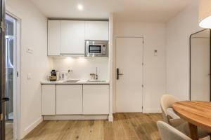 a kitchen with white cabinets and a table at Encantador apartamento Plaza del Callao in Madrid