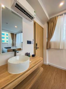 La salle de bains est pourvue d'une grande baignoire blanche et d'un grand miroir. dans l'établissement Zeus Living - City Central, à Hô-Chi-Minh-Ville