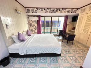 a bedroom with a large white bed with purple pillows at I Talay Lodge Botique hotel in Rayong