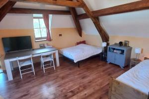 1 dormitorio con escritorio, 1 cama y TV en Escapade Rurale: Maison 10 pers, jardin, feu cheminée, en Coulonges