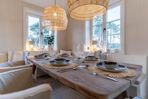 a dining room with a wooden table with chairs and lights at weivz SPO Reetdachhaus weivz SPO in Sankt Peter-Ording