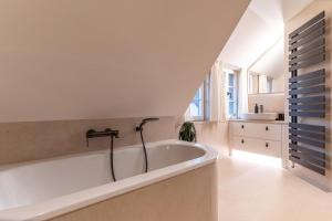 a white bath tub in a bathroom with a sink at weivz SPO Reetdachhaus weivz SPO in Sankt Peter-Ording +38 photos