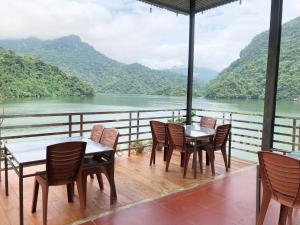 a deck with tables and chairs and a view of a river at Nhà Nghỉ Sơn Lâm - Ba Bể lake Best view in Bak Kan