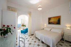 a white bedroom with a bed and a table at Il Barilotto in Positano