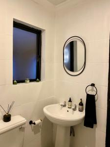 Peaceful Suburban Utopia في Sandton: حمام أبيض مع حوض ومرآة