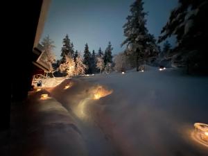 a snow covered yard with lights in the snow at Saariselällä, sielukas hirsimökki - Unique cottage in Saariselka