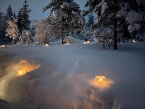a snow covered yard with lights in the snow at Saariselällä, sielukas hirsimökki - Unique cottage in Saariselka