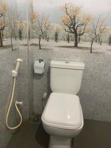 a bathroom with a toilet and a painting of trees at Sri Mali in Matara