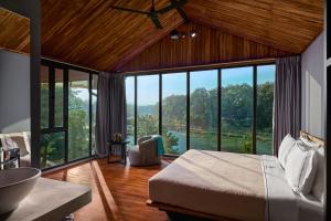 - une chambre avec un lit et une grande fenêtre dans l'établissement The Namkhan, à Luang Prabang