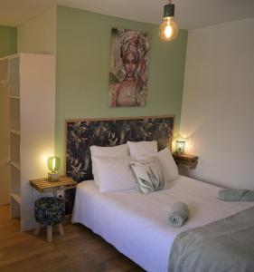 1 dormitorio con 1 cama blanca y una pintura en la pared en La bâtisse des Oves, en Le Péage-de-Roussillon