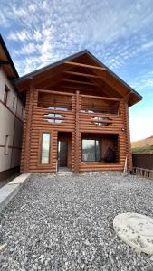 a wooden house with a gravel driveway in front of it at Байка Карпат in Vorokhta