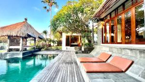 a swimming pool next to a house with orange chairs at Jabunami Villa in Canggu