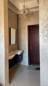 baño con lavabo, espejo y puerta en Villa near Sunset Beach, en Al Khobar