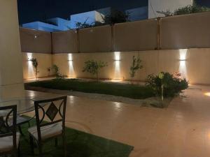 a patio with a table and chairs and a wall with lights at Villa near Sunset Beach in Al Khobar