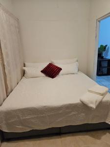 a large white bed with a red pillow on it at Dunrobyn Court Tempo Stay in East London