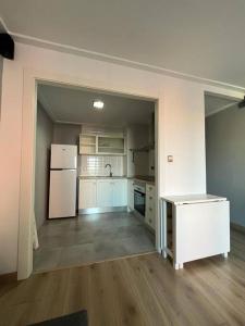 an empty room with a kitchen with a white refrigerator at La morada de Crevillent in Crevillente