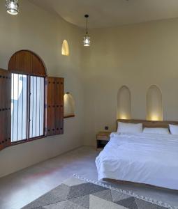 a bedroom with a large white bed and a window at بيت أرض الثراء Rich Land House in Nizwa