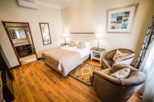 a hotel room with a bed and two chairs at AnnVilla Guesthouse in Klerksdorp