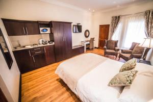 a bedroom with a large white bed and a chair at AnnVilla Guesthouse in Klerksdorp